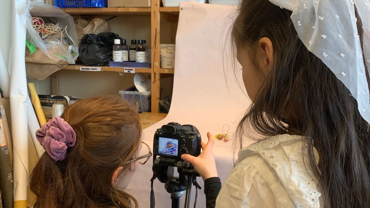 L'artiste Margaux Janisset montre à une enfant comment prendre en photo son œuvre.