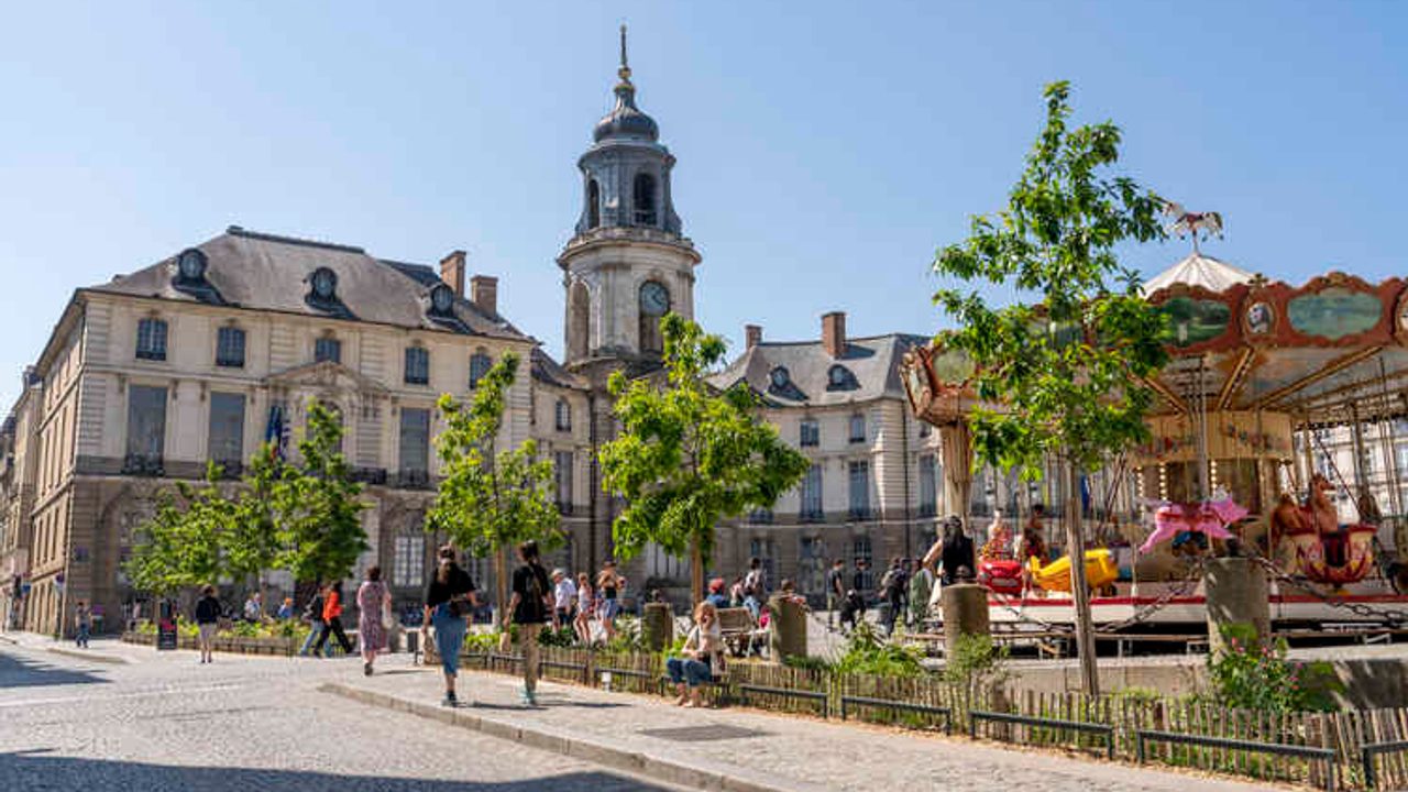 Des passants se promènent aux abords de la place de la mairie, où des chênes ont été plantés.