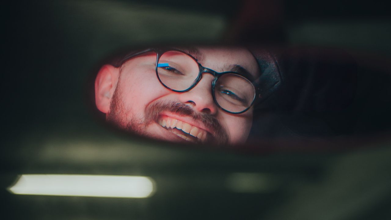 Reflet d'une personne dans le rétroviseur intérieur d'une voiture