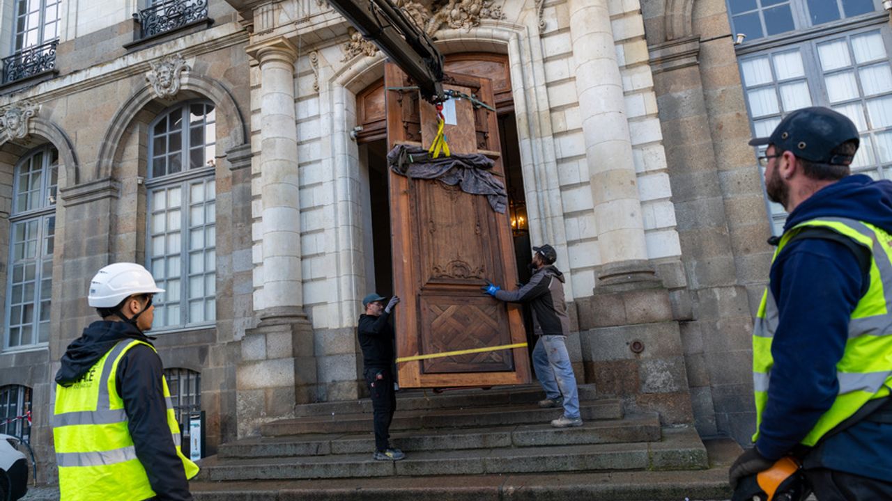 Des ouvriers portent par grue la porte pour la replacer à l'hôtel de ville