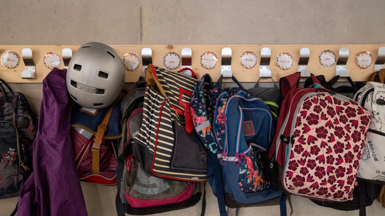 Des cartables sont suspendus dans le couloir d'une école. 