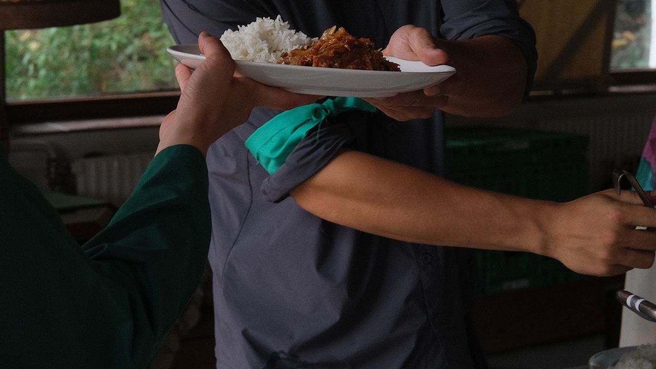 Person serving a plate of food to another