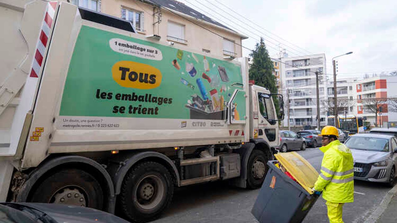 Un éboueur emmène une poubelle jaune pour la vider dans le camion de collecte d’emballages.