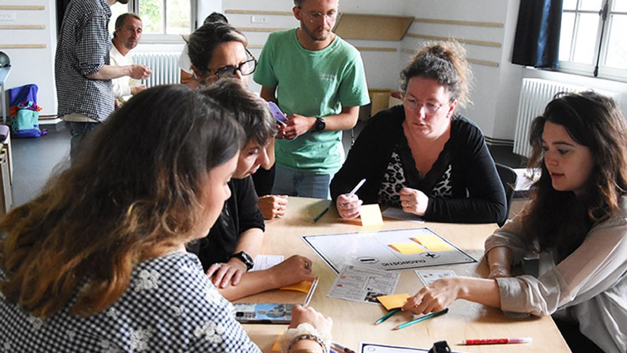 des animateurs de loisirs sont réunis sur une tables et accompagnés par des conseillers numériques