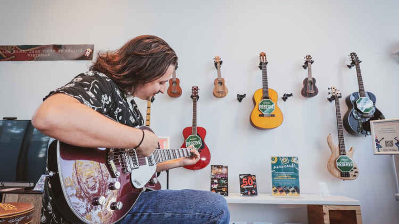Un guitariste jouant devant des instruments de prêts.