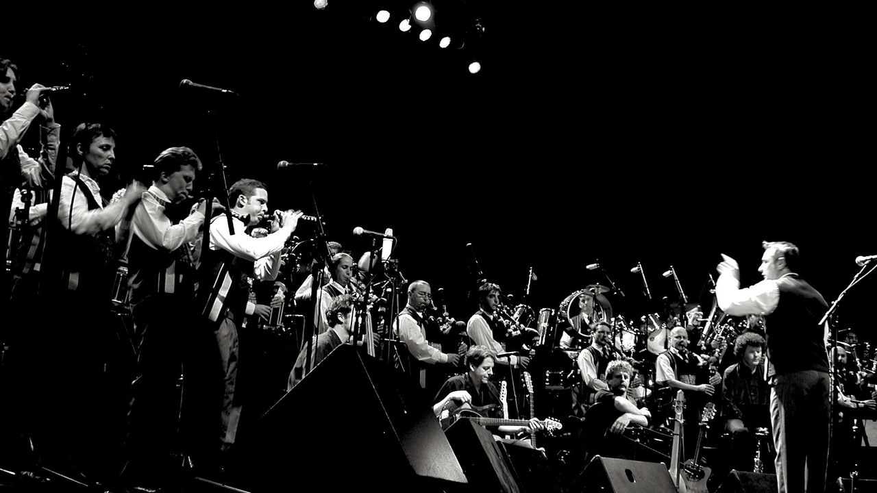 Sur scène, les musiciens d'un bagad jouent sous la houlette du chef d'orchestre.