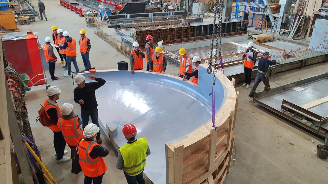 Visite de l'usine Ouest Préfa : des personnes échangent autour de la pièce béton du socle qui était alors en construction.