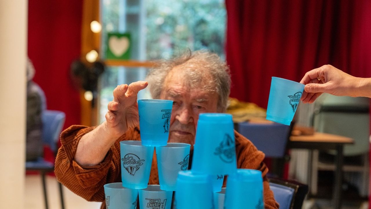 Un résident de l'Ehpad Cleunay pose un gobelet bleu en haut d'une pyramide
