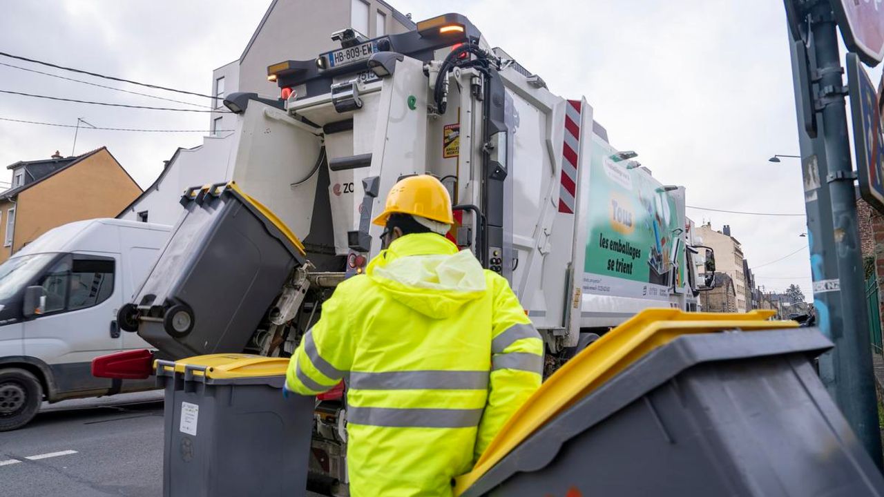Une personne en train de charger des poubelles dans le camion de collecte