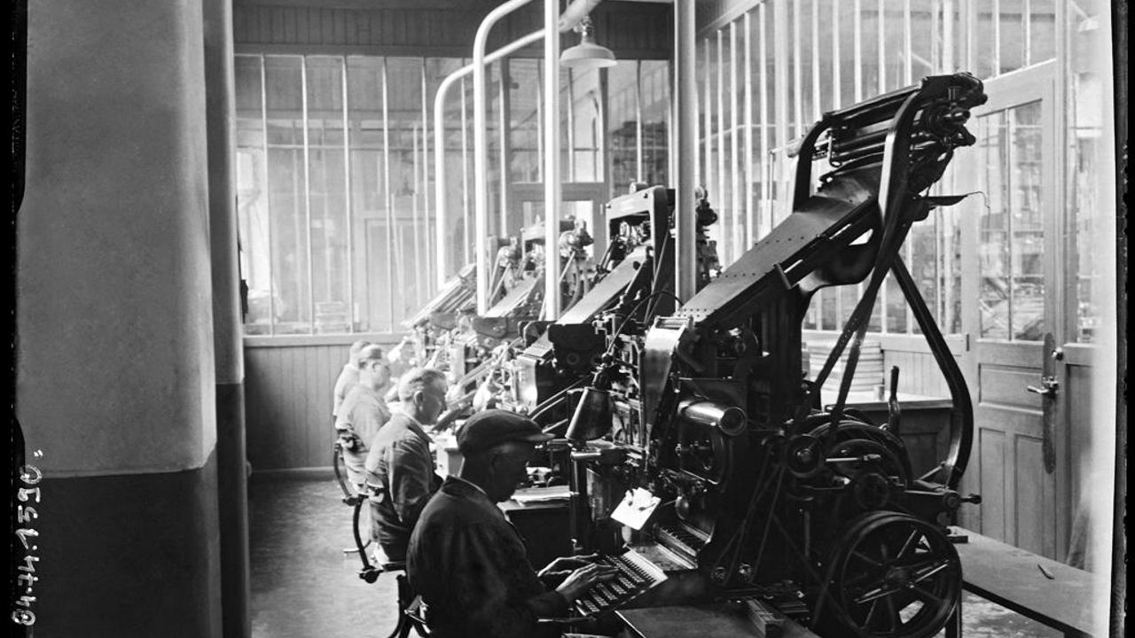 Photo en noir et blanc montrant des employés travaillant sur des machines.