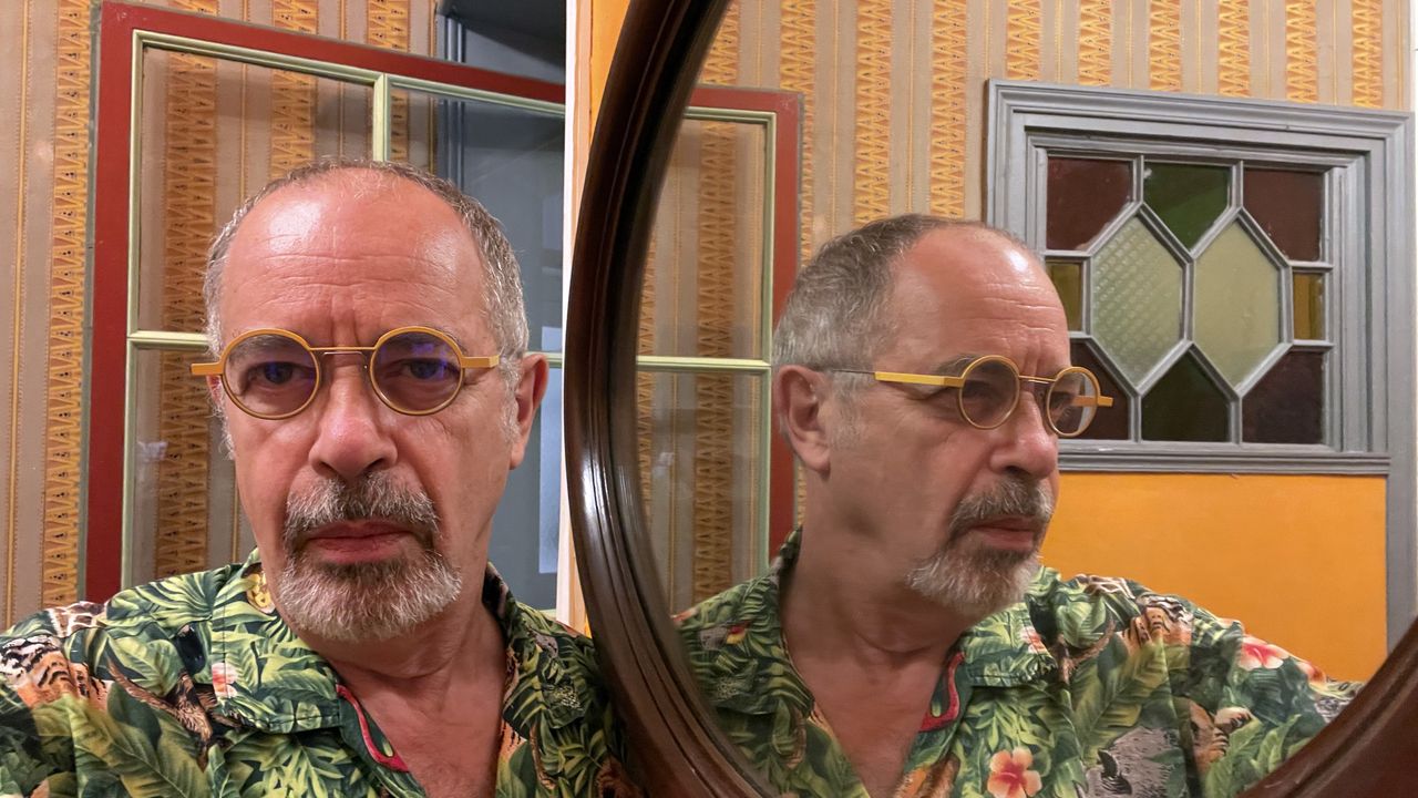 A selfie of Jean Jacques Birgé in Hawaiian shirt, close to a mirror leaving him appraisal of face and three-quarter profile.