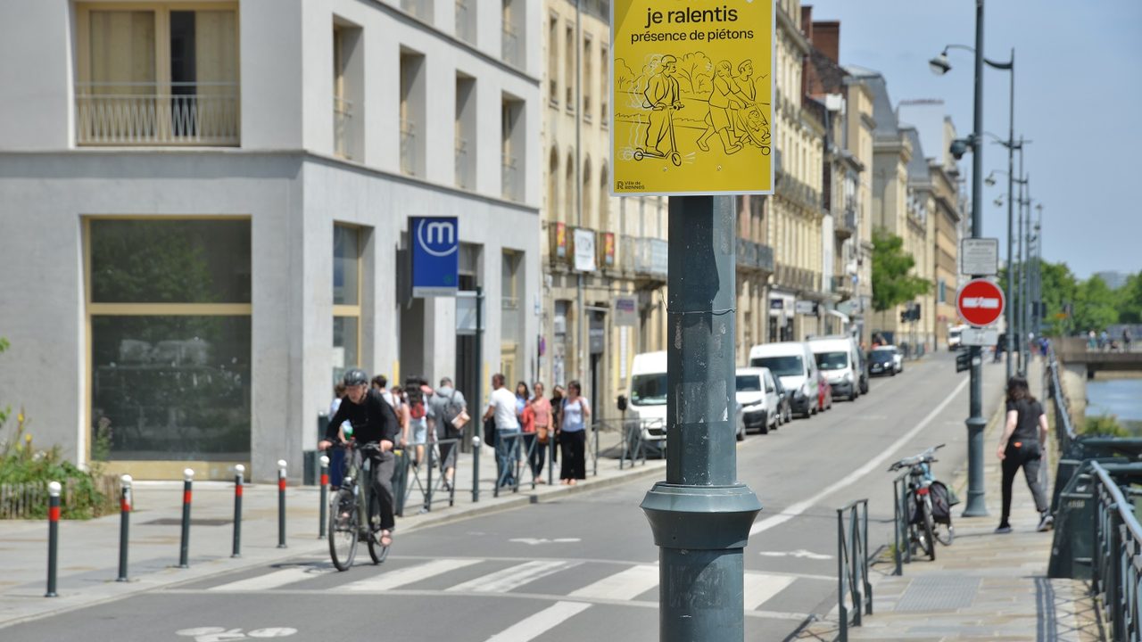Un panneau de la campagne partage de la rue place Saint-Germain, il est inscrit "Ici je ralentis, présence de piétons"