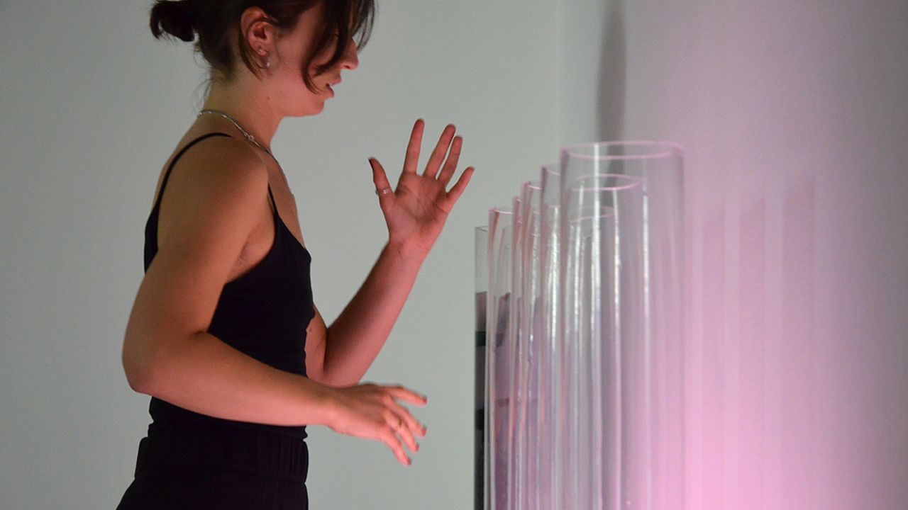 Une performeuse fait des gestes devant les vases.