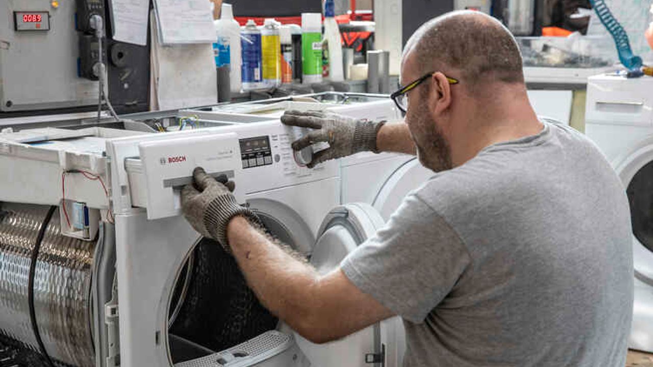 Un homme travaille pour remettre en état une machine à laver.