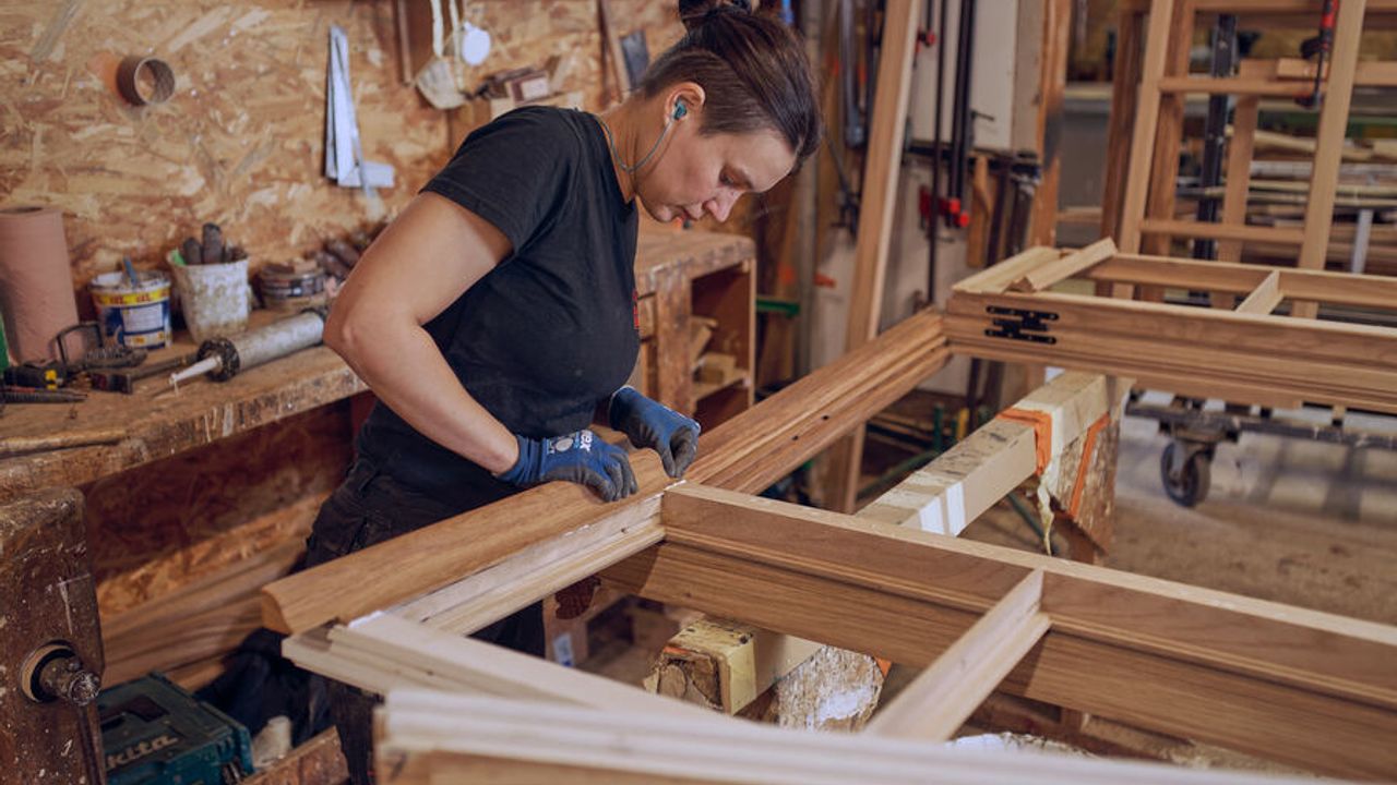 Une menuisière refabrique un cadre en bois pour solidifier la porte