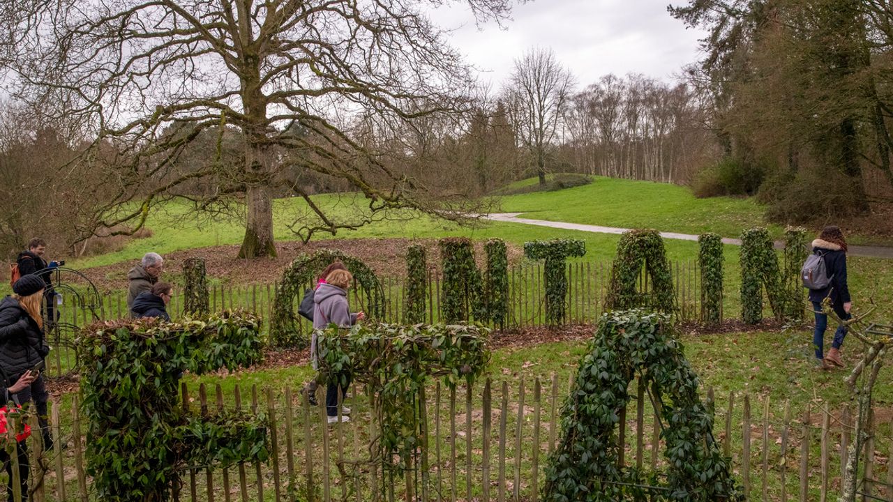 Au premier plan, des oeuvres végétales en forme de lettres constituent la phrase "Il était une fois dans un pays lointain" au milieu d'un parc