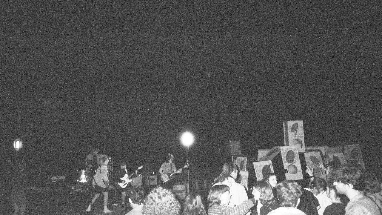 Stage with a band playing and crowd dancing. At night, black and white picture