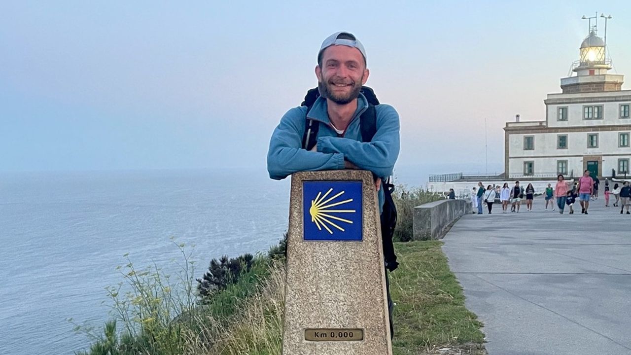 Le jeune homme pose devant le symbole de Saint Jacques de Compostelle