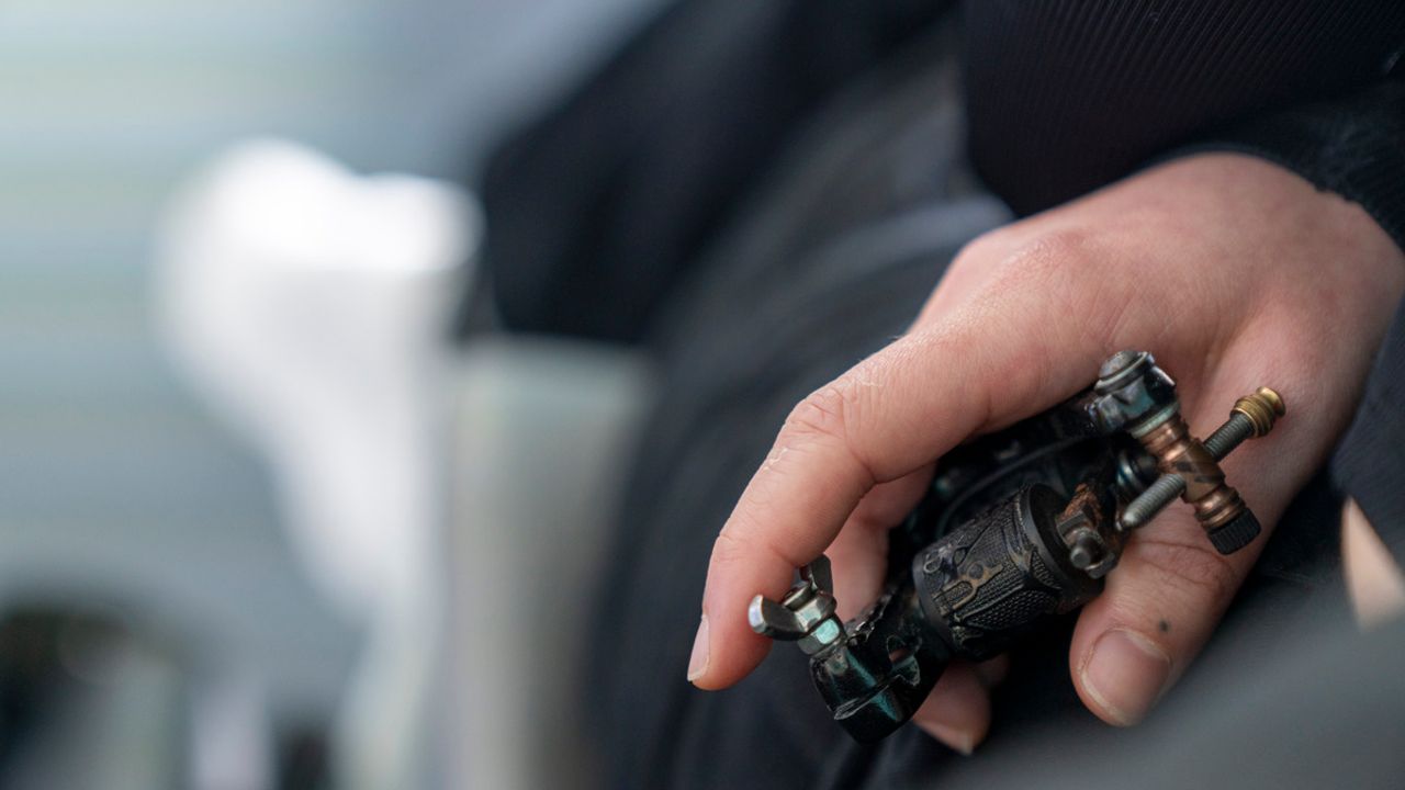 Gros plan sur une main tenant une machine à tatouer