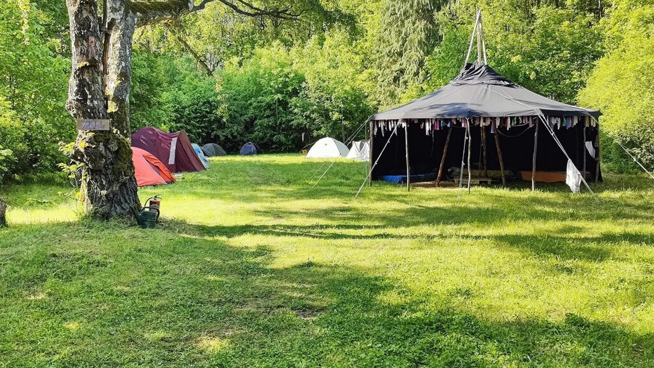 Camping site, with a few tents propped up and a bigger event tent