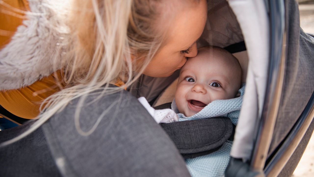 Une maman avec son bébé dans un couffin.
