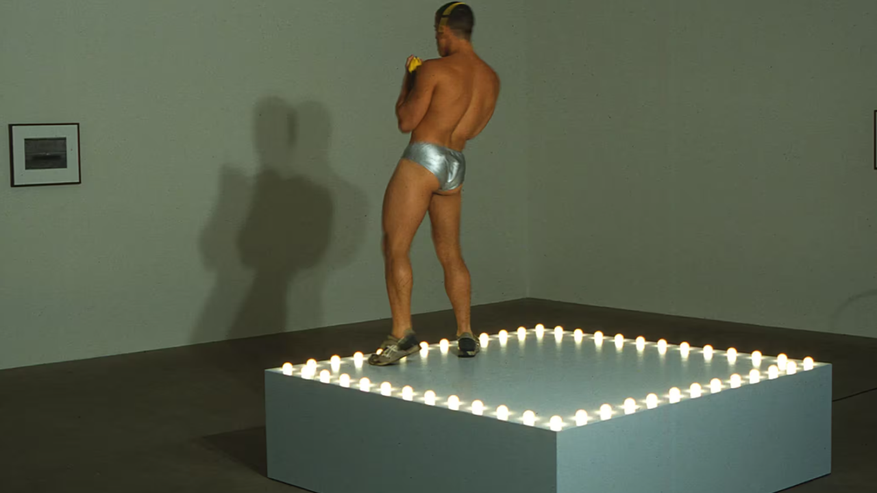 Sur la photographie de l'installation de Gonzalez-Torres, un homme danse seul sur une plateforme, vêtu d'un sous-vêtement argenté.