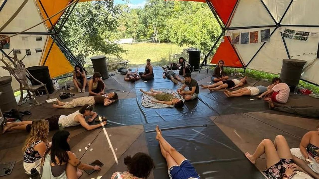 people lying down on the floor of a stage inside dome structure, attending a workshop