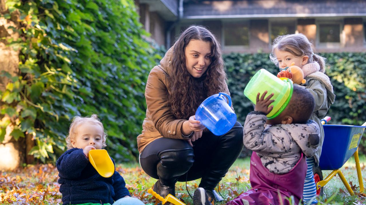 Des enfants jouent dehors avec une professionnelle de la petite enfance.