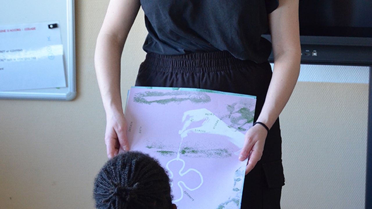 L'artiste Margaux Janisset montre une affiche aux élèves.