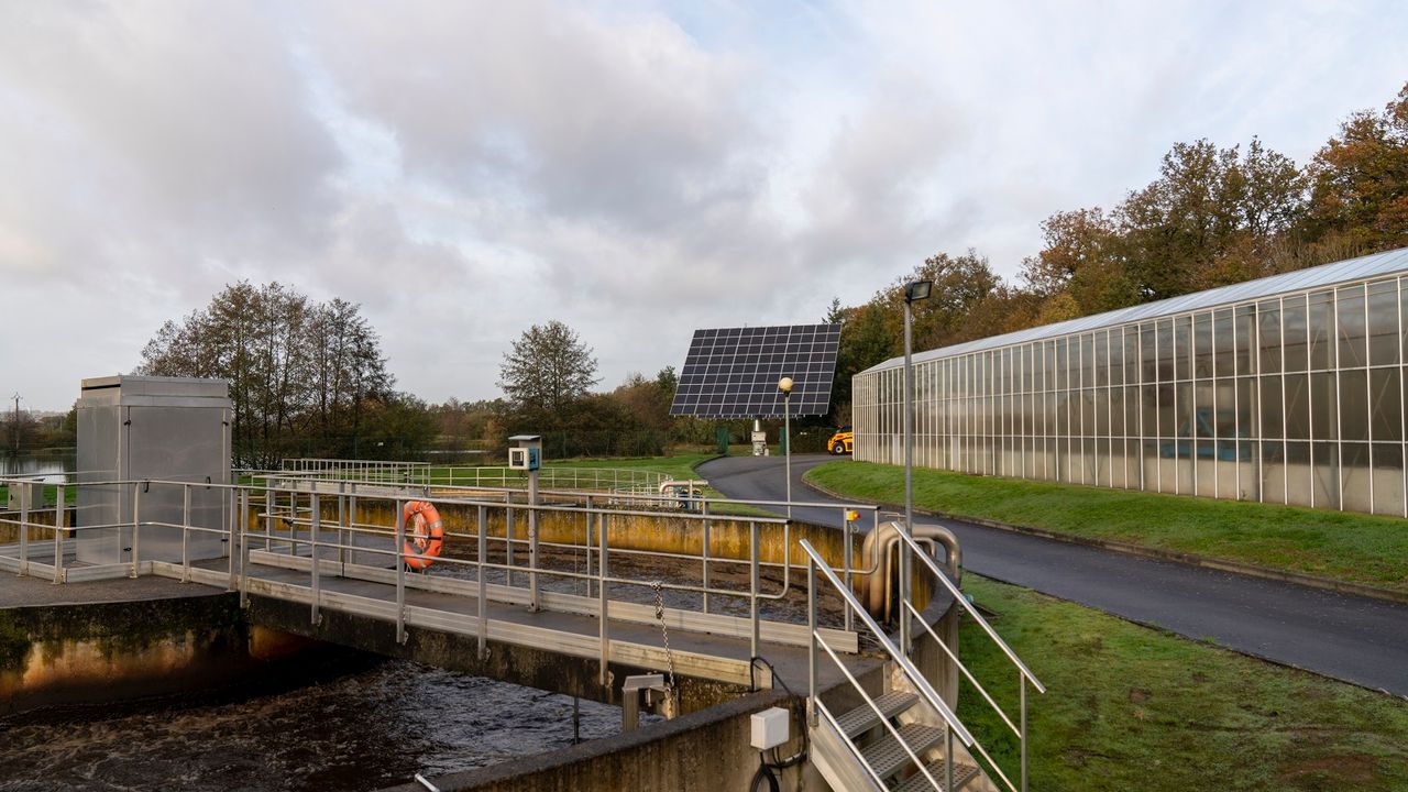 Photo de la station d'épuration de Laillé. Au premier plan, un bassin d'aération, au deuxième plan les panneaux photovoltaïques installés sur le site.  