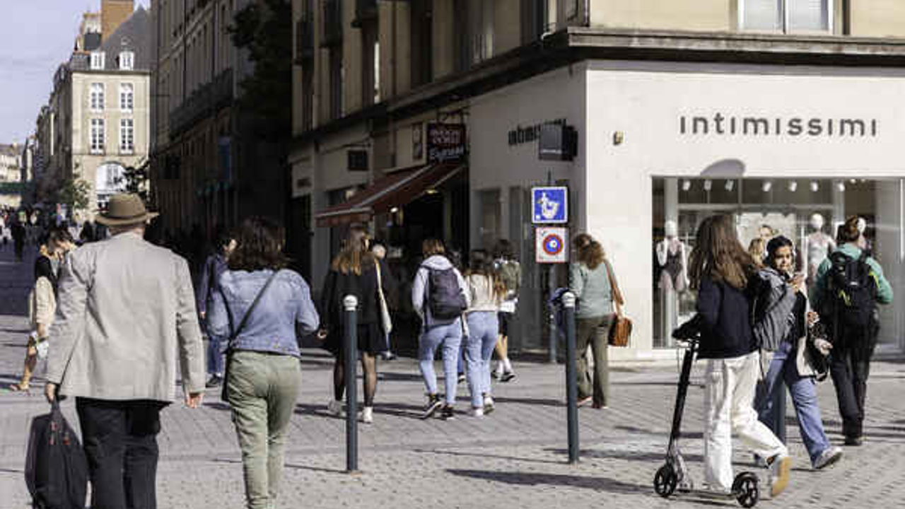 Des passants vus de dos dans une rue commerçante de Rennes.