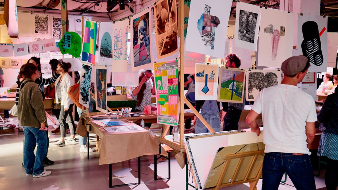 Des stands d’affiches colorés, avec des personnes qui se promènent dans les allées.