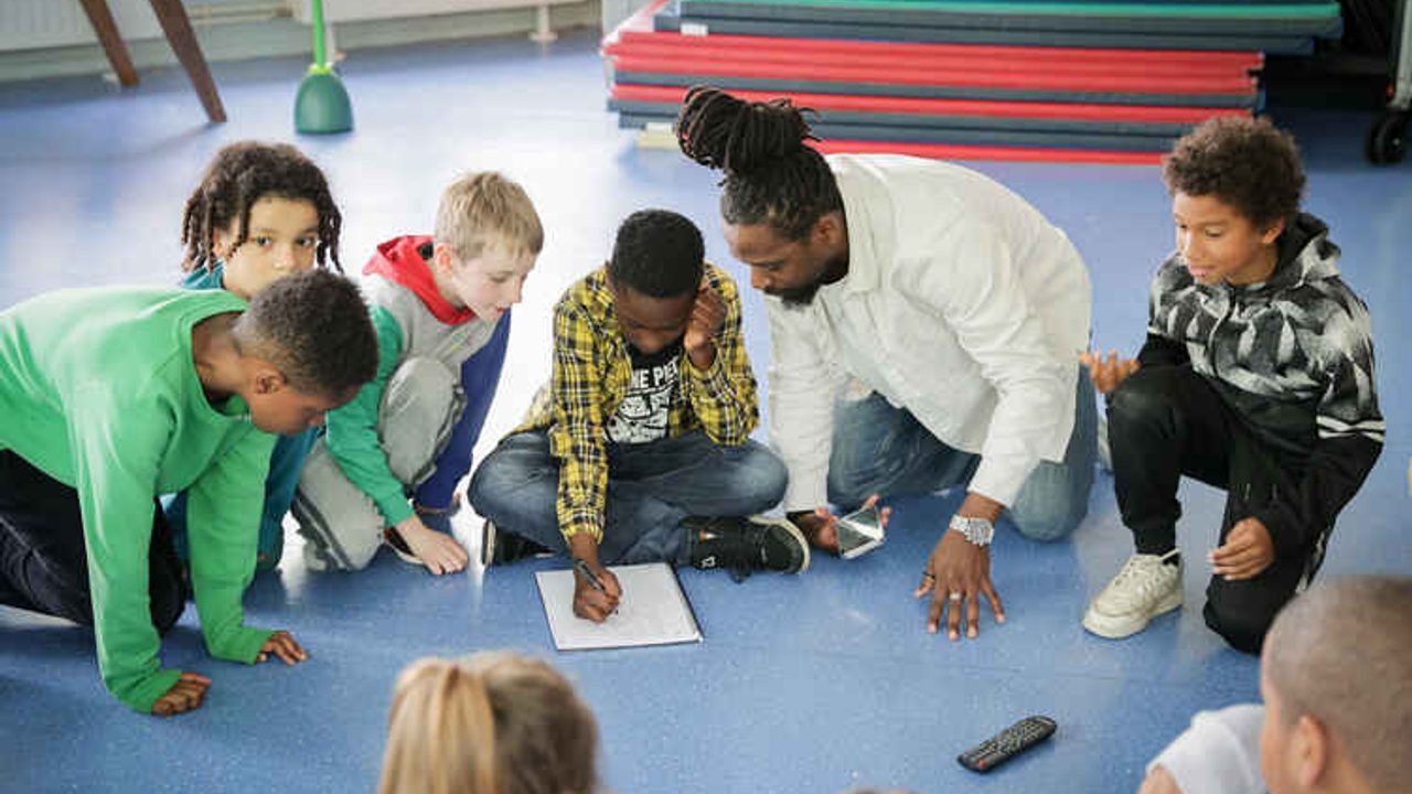Des enfants assis en rond avec un animateur qui donne des consignes.