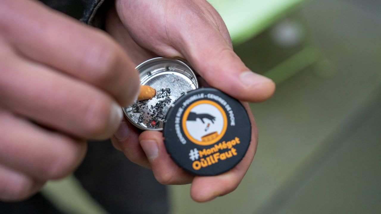 Une personne écrase son mégot dans un cendrier de poche. 