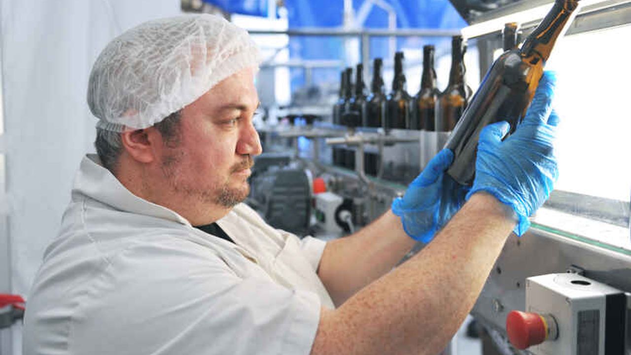 Un employé vérifie les bouteilles nettoyées sur une chaîne de production