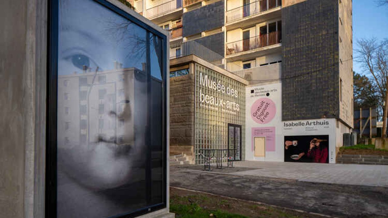 Vue sur l'entrée du musée des beaux arts de Maurepas en pied d'immeuble, avec des affiches d'exposition
