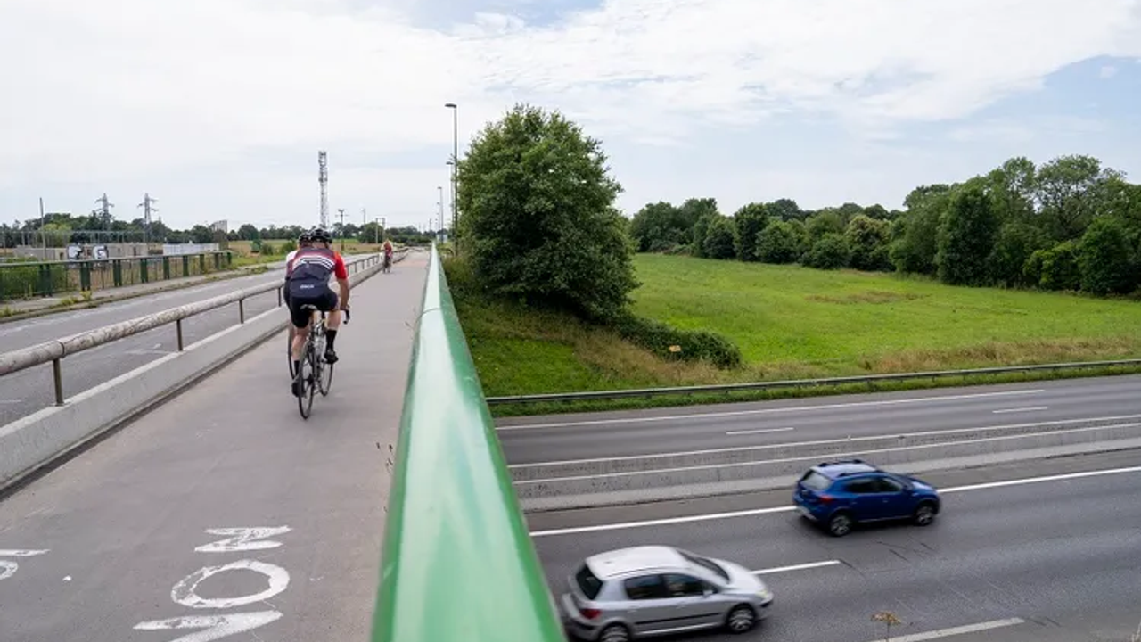 Photo de la voie cyclable avec cyclistes qui enjambe la rocade où roulent des voitures.