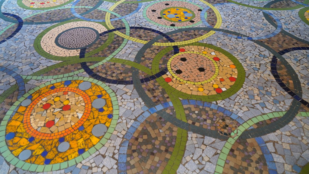 Détail d'une mosaïque au sol d'un magasin de la galerie du théâtre : cercles colorés qui s'entrecroisent.