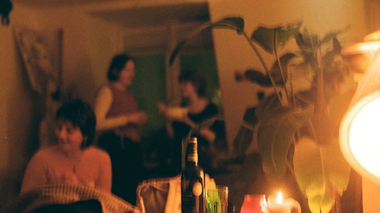 Candle lit room, with people sitting and standing around talking to each other