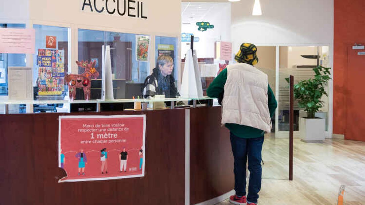 Une femme à un comptoir d’accueil d’un Centre communal d'action sociale face une autre personne.