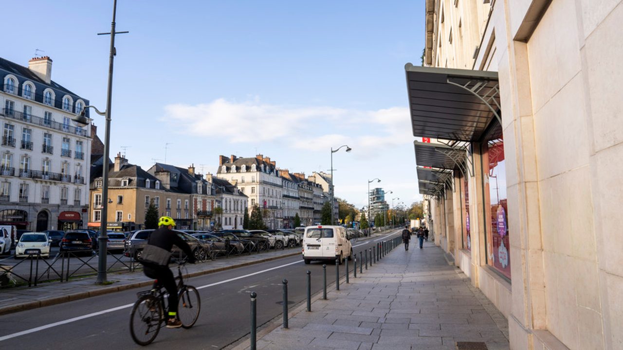 Vue du parking Vilaine depuis le début du quai Duguay-Trouin, avec au premier plan le trottoir bordant le quai, au centre un cycliste sur la rue et le parking en second plan.