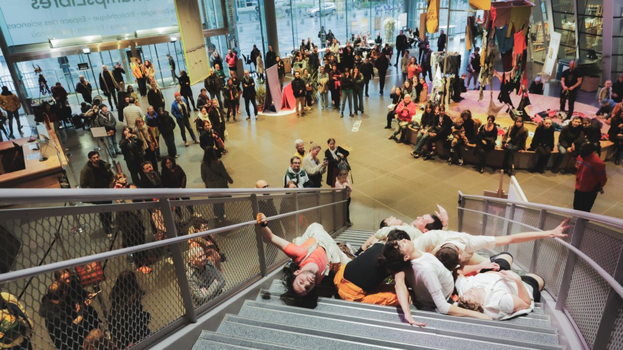 Hall des Champs libres, avec au premier plan un grand escalier où des personnes se produisent lors d’une performance.