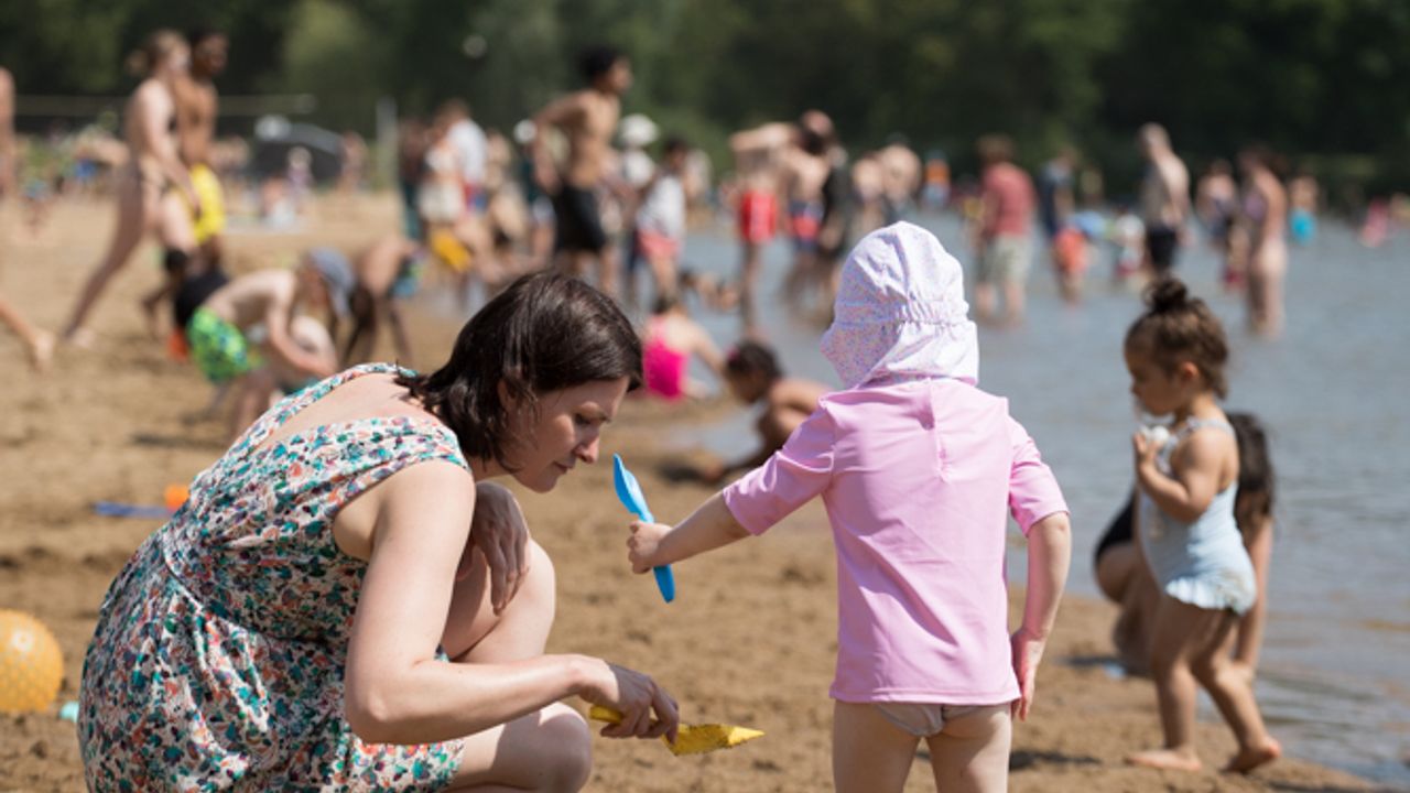 Mère et enfant sur la plage des Etangs d'Apigné à jouer avec un seau et une pelle en été 