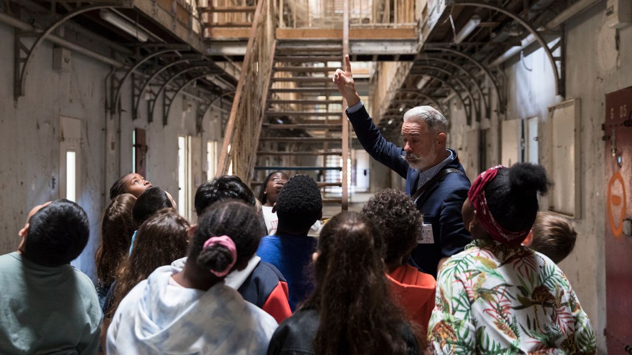 Des enfants de dos, découvrent la prison avec un médiateur