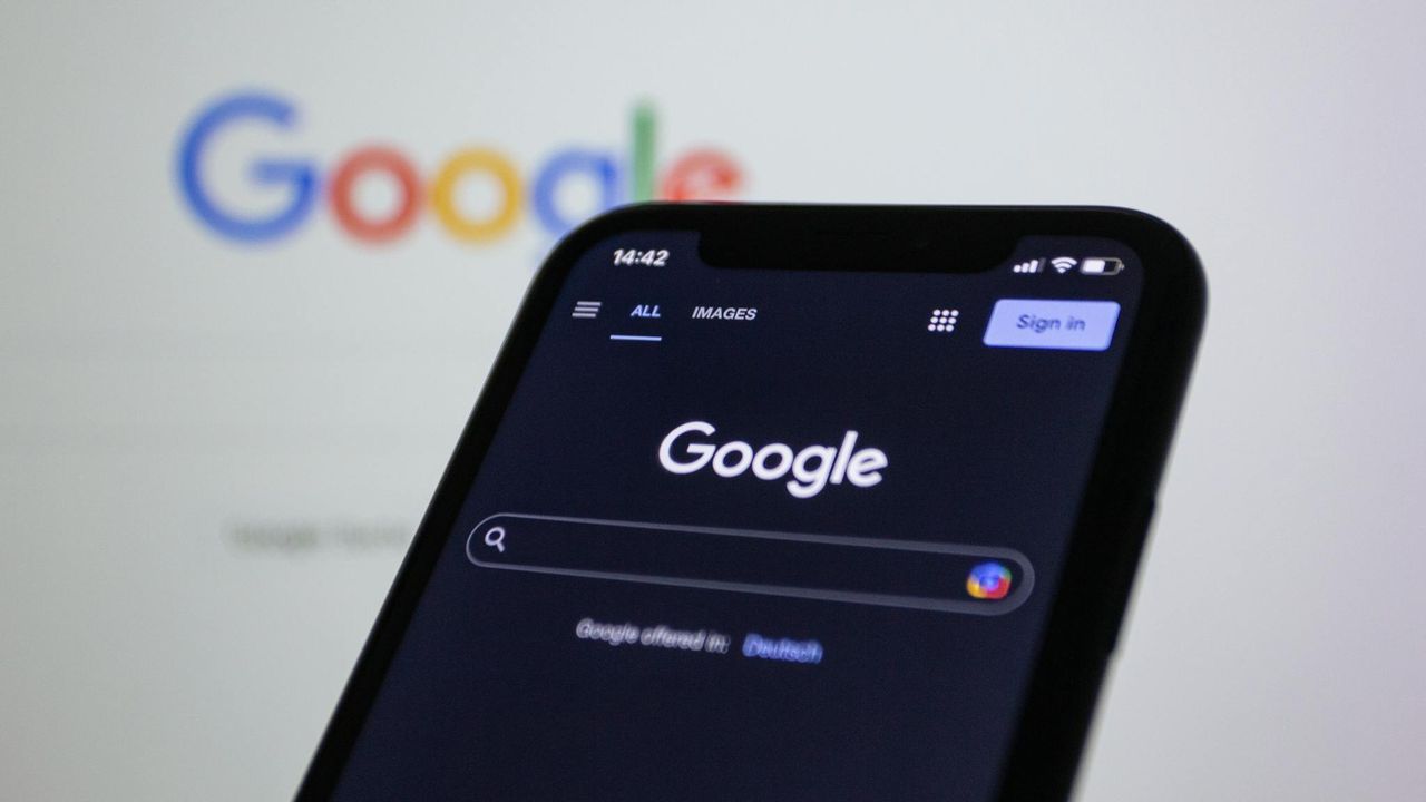 Google on a mobile phone and Google logo in background