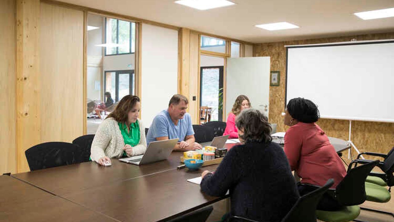 Cinq personnes en réunion autour d’une table.