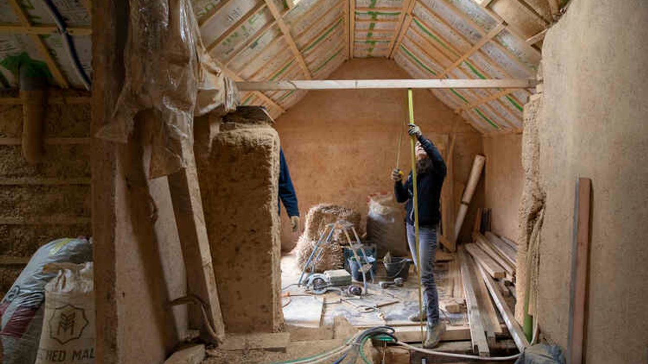 Importants travaux d'isolation à l'intérieur d'une maison individuelle. Une femme prend des mesures sous le toit.