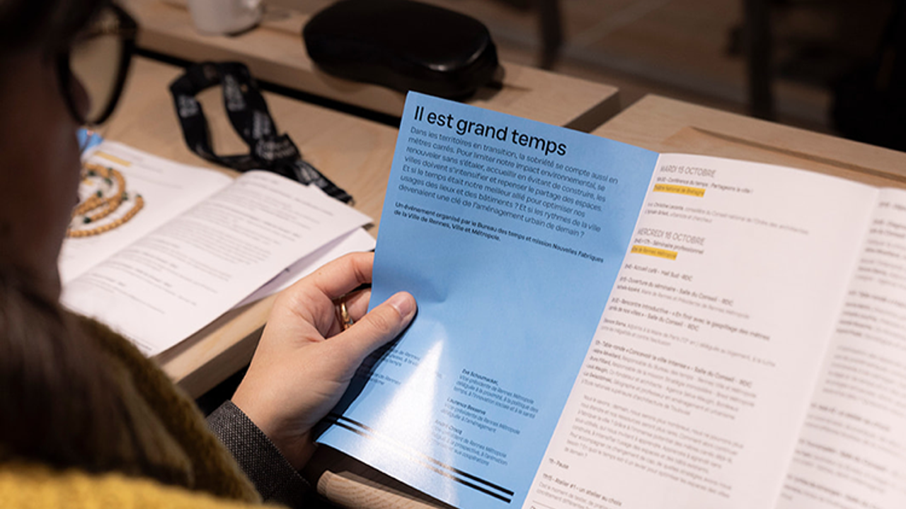 une femme tient dans ses mains un dépliant sur le séminaire de la chronotopie