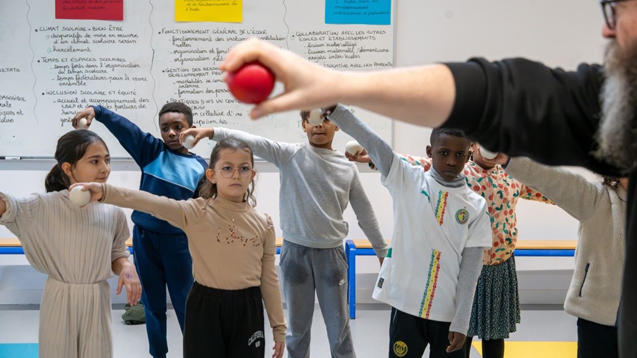 Des enfants tiennent une balle de jonglage au bout de leur bras tendu