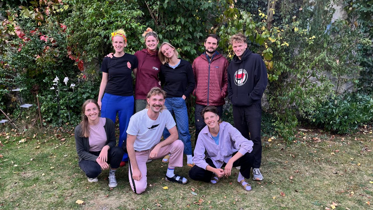 Degrowth Vienna team (8 people), posing together outside in the grass, looking cute.